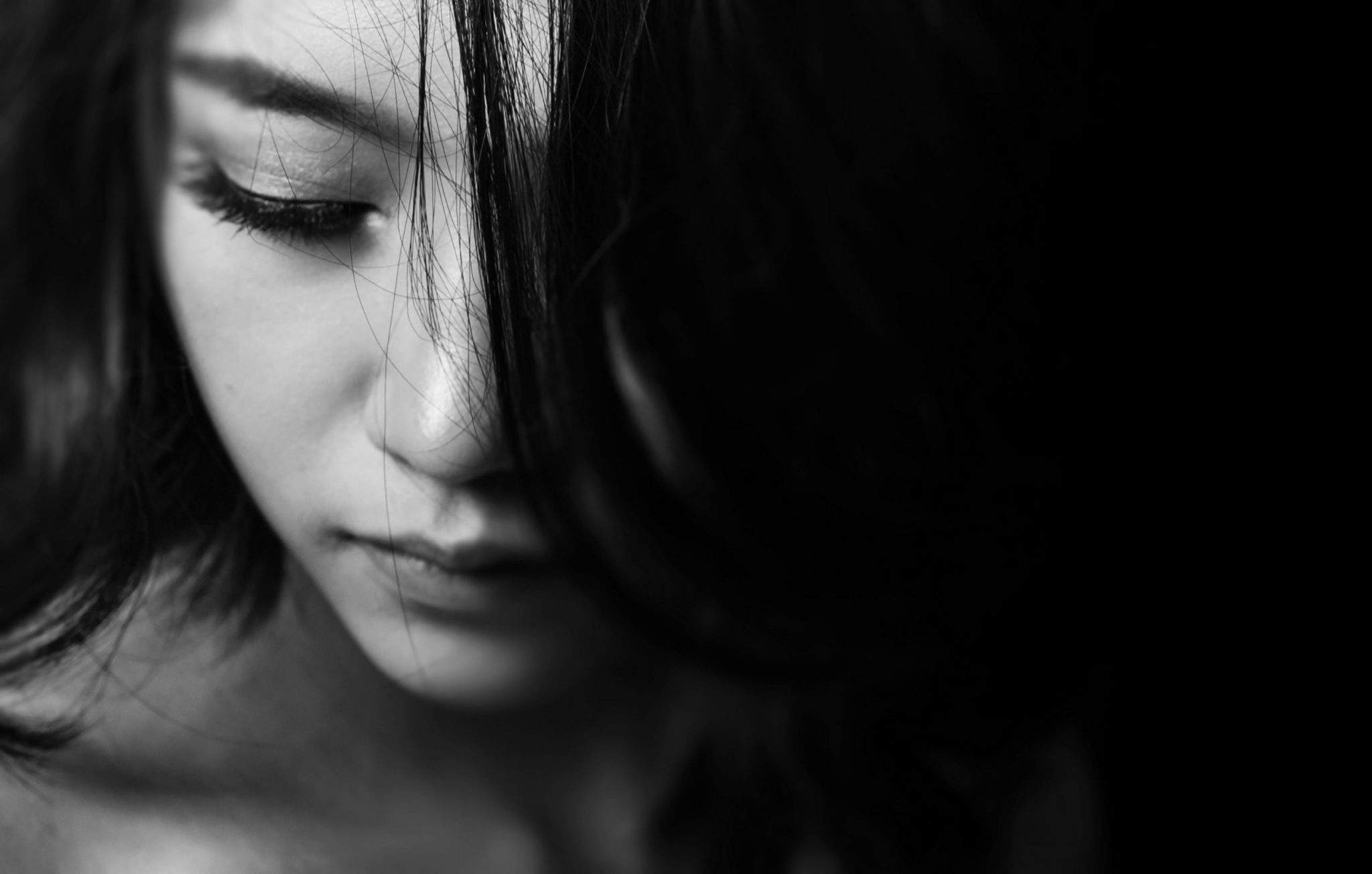 black and white image of womans face in shadows looking down