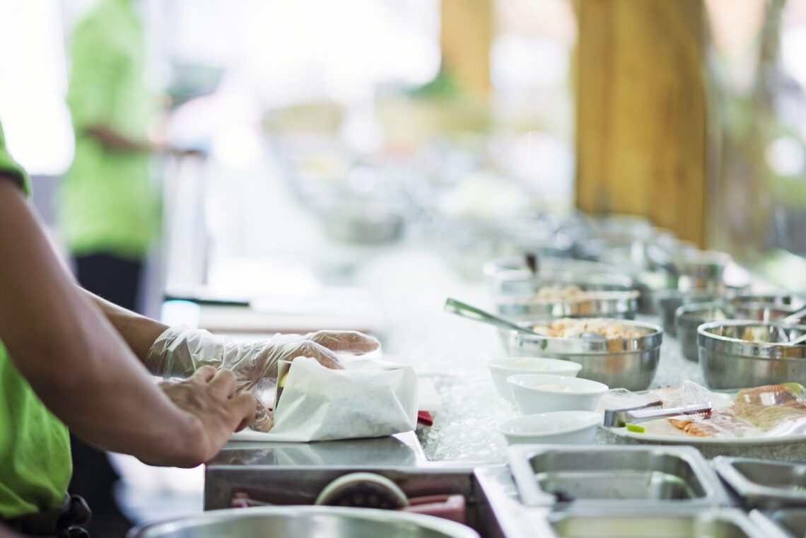image of someone's hands in kitchen wrapping a sandwich to give out